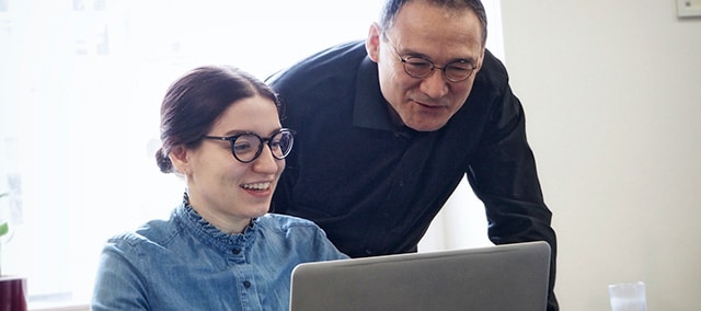 Mann und Frau sitzen lachend vor Laptop