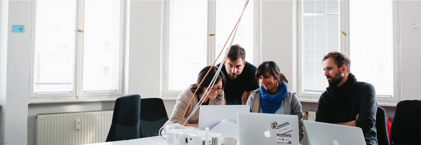 Four people working together, looking at one screen