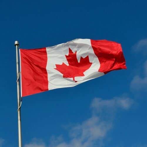 A canadian flag waving in front of blue sky