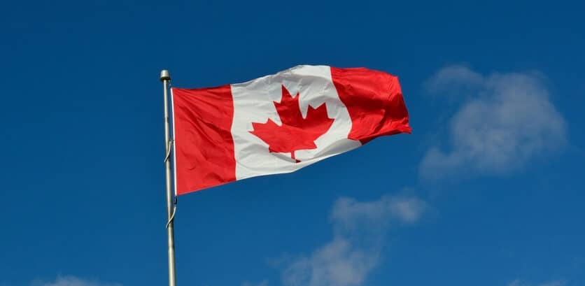 A canadian flag waving in front of blue sky